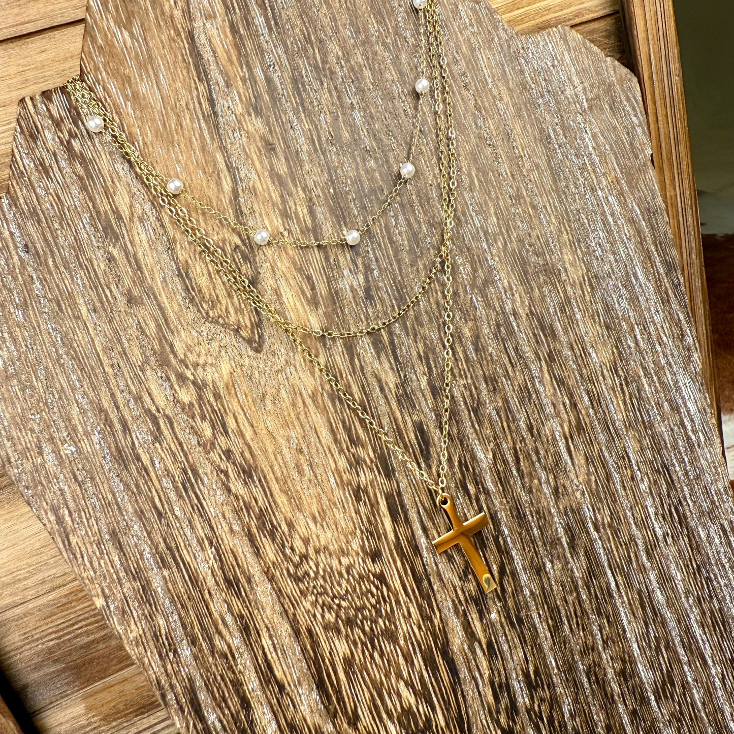 Gold necklace with a cross pendant on a wooden surface