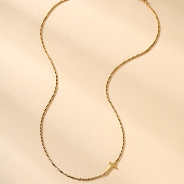 Gold necklace with a cross pendant on a beige background faith based jewelry for women