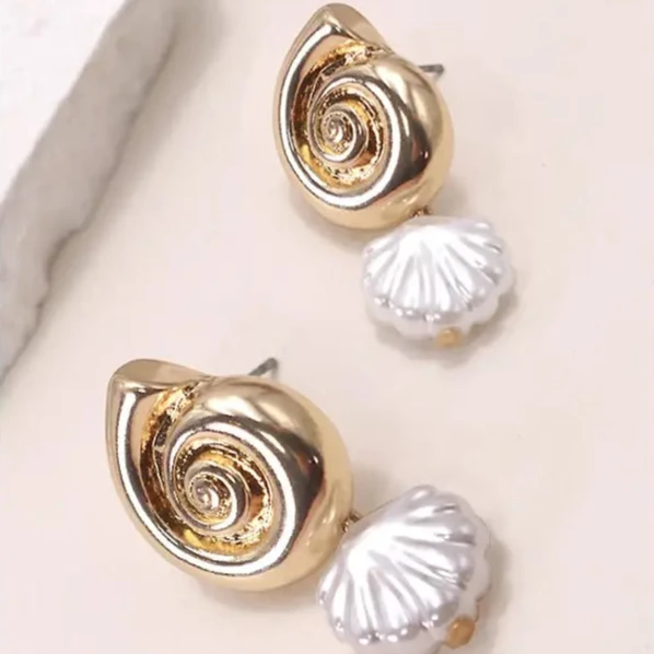 Pair of gold shell-shaped earrings on a light pink background