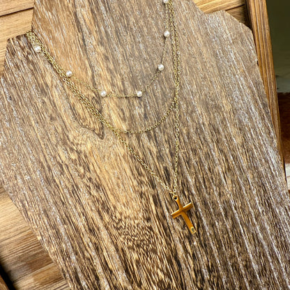 Gold necklace with a cross pendant on a wooden surface