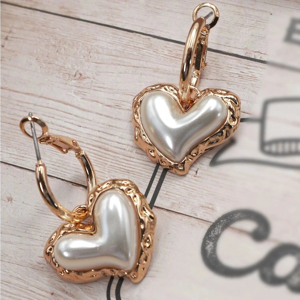 Heart-shaped earrings with gold and pearl details. Women's feminine and classy jewelry.