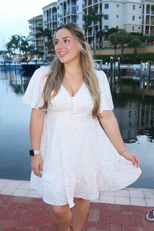 women standing infront of a waterfront wearing white and purple floral print mini dress