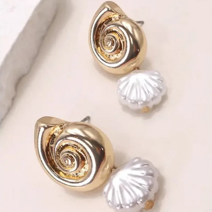 Pair of gold shell-shaped earrings on a light pink background